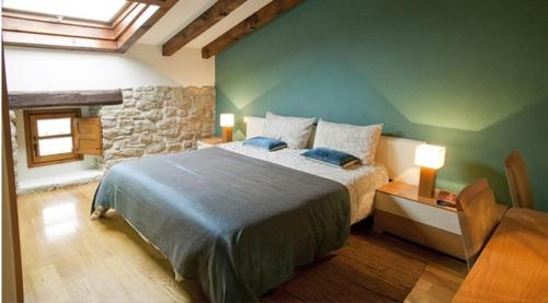 Garínoain拉克阿克乡村民宿的一间卧室设有一张大床和石墙