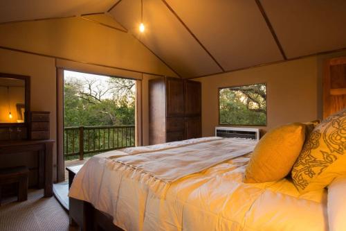 侯斯普瑞特Vuyani River Lodge的一间卧室配有一张床,阳台配有两个窗户