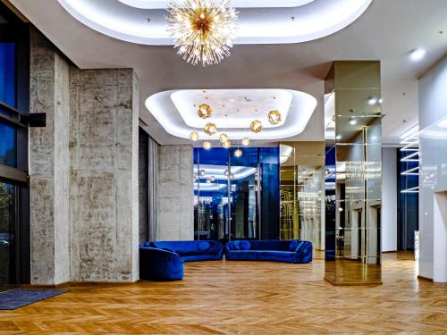 布加勒斯特Union Plaza Hotel的大堂设有蓝色的沙发和吊灯。