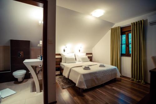 普利特维采湖金湖酒店的一间卧室设有一张床、一个卫生间和一个水槽