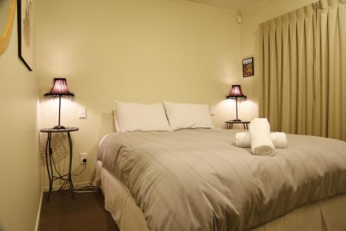 奥阿库尼奥阿库尼洛矶山木屋的一间卧室配有一张带两盏灯的大型白色床。