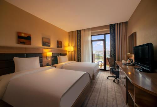 伊斯坦布尔Dosso Dossi Hotels & SPA Golden Horn的酒店客房设有两张床、一张桌子和一台电视。