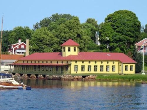 乌德瓦拉Gustafsbergs Badhotell & Vandrarhem的一座黄色的大建筑,在水面上有一个红色的屋顶