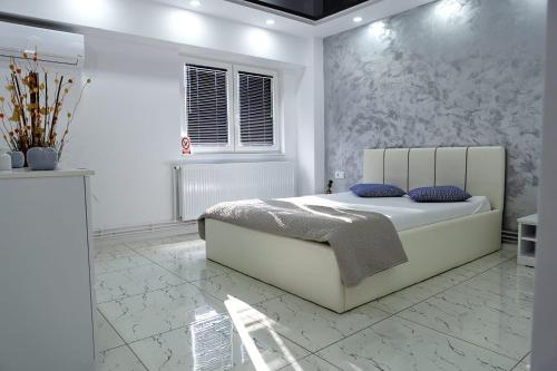 加拉茨Archi's Apartament的白色卧室配有一张带蓝色枕头的大床