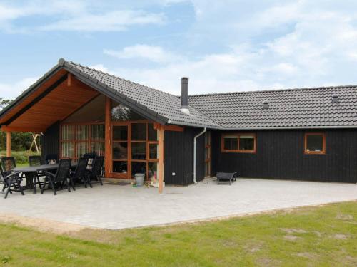 瓦伊厄斯斯特兰德8 person holiday home in Vejers Strand的黑色的房子,设有庭院和桌子