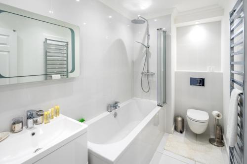 伦敦Stunning 2-bed flat w/ garden patio in West London的白色的浴室设有浴缸和水槽。