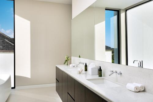 Long Bay HillsUXUE Villa的一间带两个盥洗盆和大镜子的浴室
