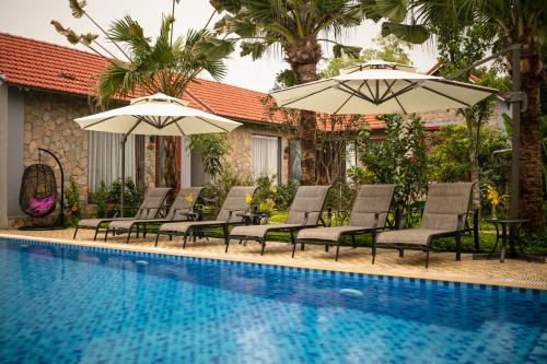 宁平Tam Coc Holiday Hotel & Villa的一组椅子和遮阳伞,位于游泳池旁
