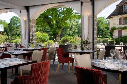 多尔多尼河畔博利厄Logis hotel les flots bleus的餐厅设有桌椅和大窗户。