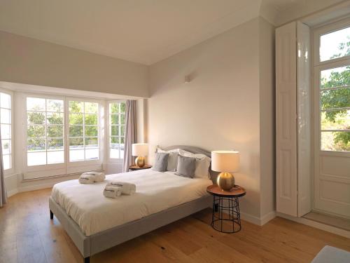 波尔图FLH Seaside Luxury House in Porto的一间卧室配有一张带两盏灯的床和两扇窗户。