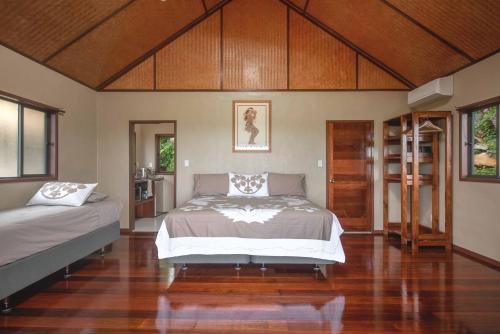 拉罗汤加Rainbow Villas的一间卧室设有两张床,铺有木地板