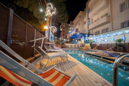 里米尼里米尼科拉洛酒店的一座带躺椅的游泳池位于大楼旁