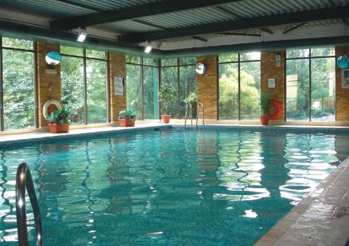 布拉姆霍普大不列颠利兹布拉福德机场酒店的一座大型游泳池,位于一座带窗户的建筑内
