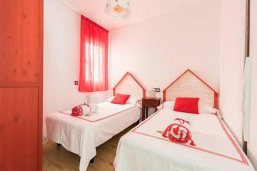 马德里Visitor's Book的一间卧室配有两张带红色枕头的床。