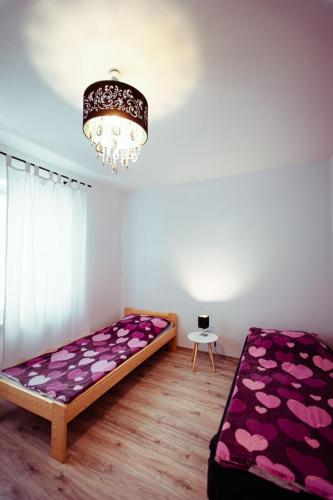 比乌戈拉伊Miejskie Zacisze的一间卧室配有一张带紫色床单和吊灯的床。