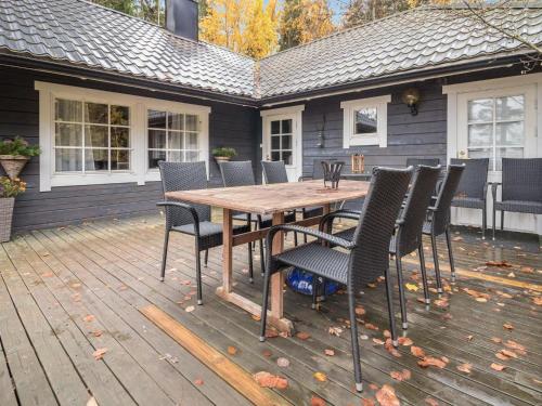 TallnäsHoliday Home Lohjanherra by Interhome的甲板上的木桌和椅子