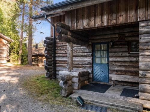 拉赫登佩拉Holiday Home Vuokatinportti a7 by Interhome的小木屋,有一扇蓝色的门和一堆木头