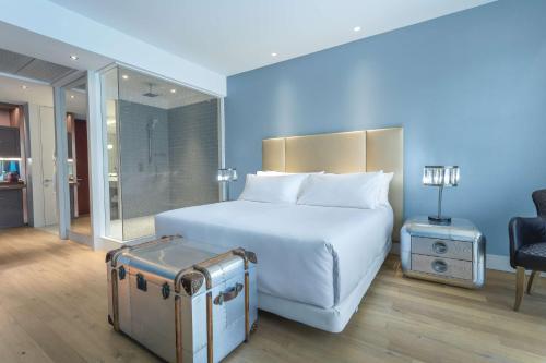 圣地亚哥NH Collection Santiago Casacostanera的酒店客房带白色的床和手提箱