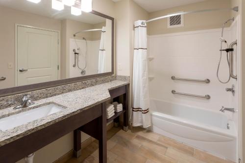 Cannon FallsGrandStay Hotel & Suites的一间带水槽、浴缸和镜子的浴室