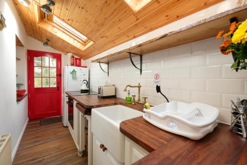 韦斯特波特The Cottage Hillside的一个带水槽和红色门的厨房