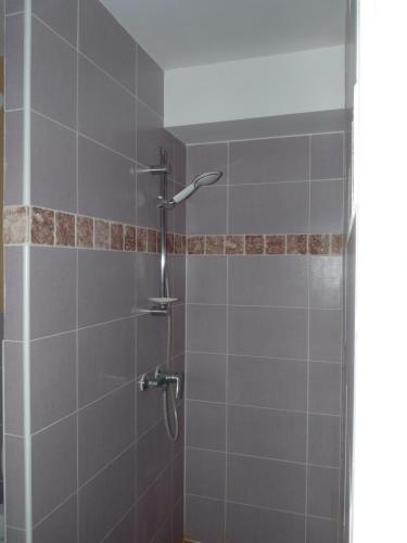 Crévouxla grange的浴室铺有灰色瓷砖,设有淋浴。