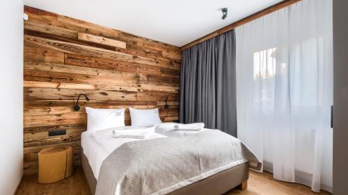 卡尔帕奇Domki w Karpaczu SARNIA Sun & Snow - z Kominkami的一间卧室设有木墙和一张床