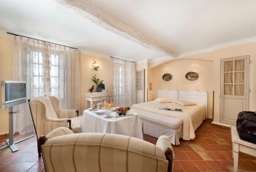 格拉斯Bastide Saint Antoine - Relais & Châteaux的卧室配有一张床和一张桌子及椅子