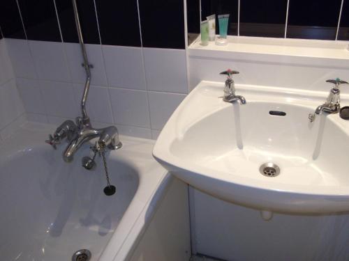 考文垂大不列颠考文垂山酒店的浴室配有盥洗盆和浴缸。