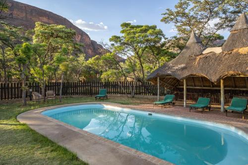 Golders GreenEntabeni Hospitality Pty Ltd的一个带椅子的庭院和小屋内的游泳池