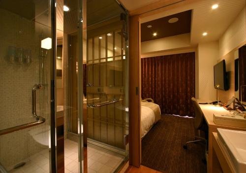 高崎可可大酒店的带淋浴的浴室和客房内的一张床