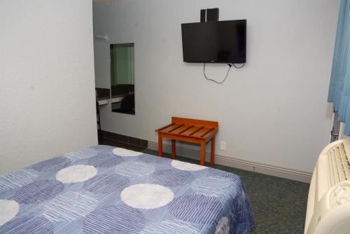 洛杉矶彗星汽车旅馆的卧室配有一张床,墙上配有电视。