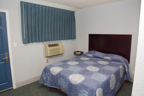 洛杉矶彗星汽车旅馆的一间卧室配有一张床和一个带风扇的窗户。