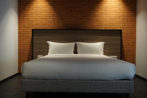 丹吉尔ONOMO Hotel Tanger Med的一张带白色枕头和砖墙的大床