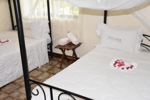 姆托瓦姆布凡纳卡游猎营地山林小屋的配有2张床铺的白色床单和鲜花