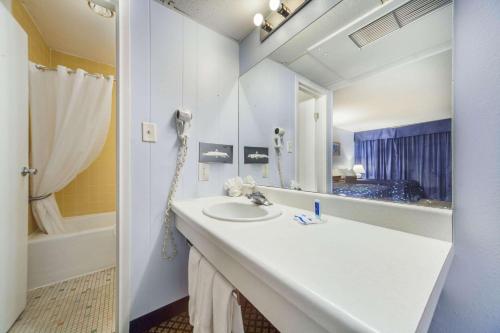 北普拉特Hospitality Inn的浴室配有盥洗盆、镜子和浴缸