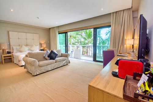 长滩岛卡米拉海滩度假村别墅的一间卧室配有一张床、一张沙发和一台电视