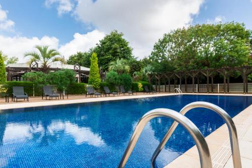 布格奈斯大洋洲南特酒店的一个带椅子和树木的大型游泳池