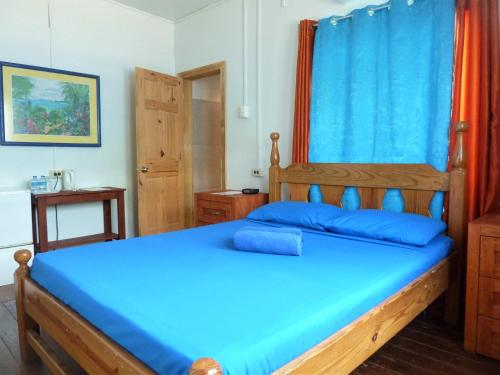 Buccoo米勒旅馆的一间卧室配有一张带蓝色床单的木床。