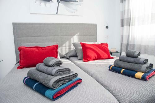 美洲海滩Playa de Las Americas Luxury Home的一张带毛巾和红色枕头的床