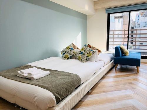 大阪WELLSTAY Honmachi的一间卧室配有一张大床和一张蓝色椅子
