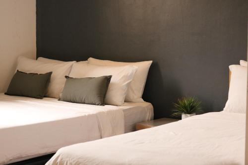 哥打京那巴鲁IKO homes的两张带白色床单和绿色枕头的床