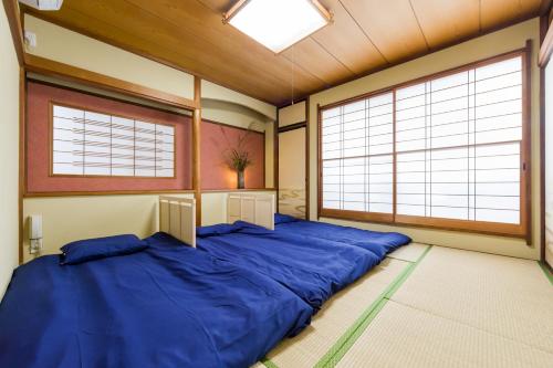 静冈Tessen Guesthouse的一张大蓝色的床,位于带两个大窗户的房间