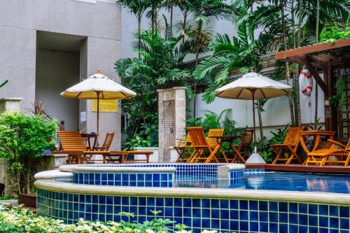 曼谷Silom Serene A Boutique Hotel - SHA Extra Plus的一个带桌椅和遮阳伞的游泳池
