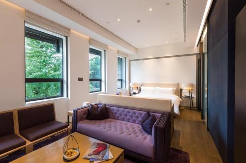 成都成都钓鱼台精品酒店的酒店客房设有一张床和一张紫色沙发