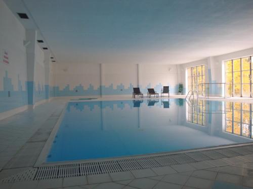 图赫洛维采阿斯特拉酒店的大楼内一个带两把椅子的大型游泳池