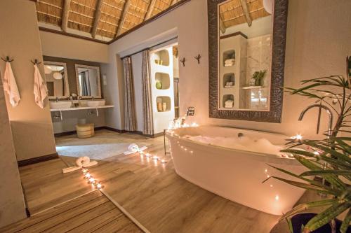萨比沙禁猎区辛班比利荆棘山林小屋的地板上设有带灯光的浴缸的浴室