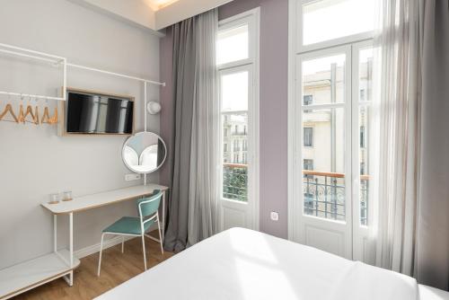 塞萨洛尼基Colors Urban Hotel Thessaloniki的一间卧室配有一张床、一张书桌和一个窗户。