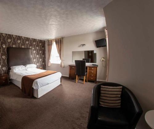 伍德哈姆斐尔斯奥克兰酒店的一间卧室配有一张床、一张桌子和一把椅子