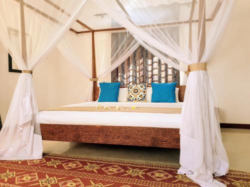 布韦朱Villa Oman的一间卧室配有一张带蓝色枕头的天蓬床