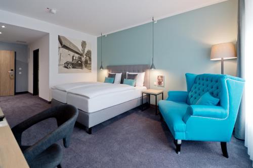 Niederzier伯格奥本多尔夫酒店的一间卧室配有一张床和一张蓝色椅子